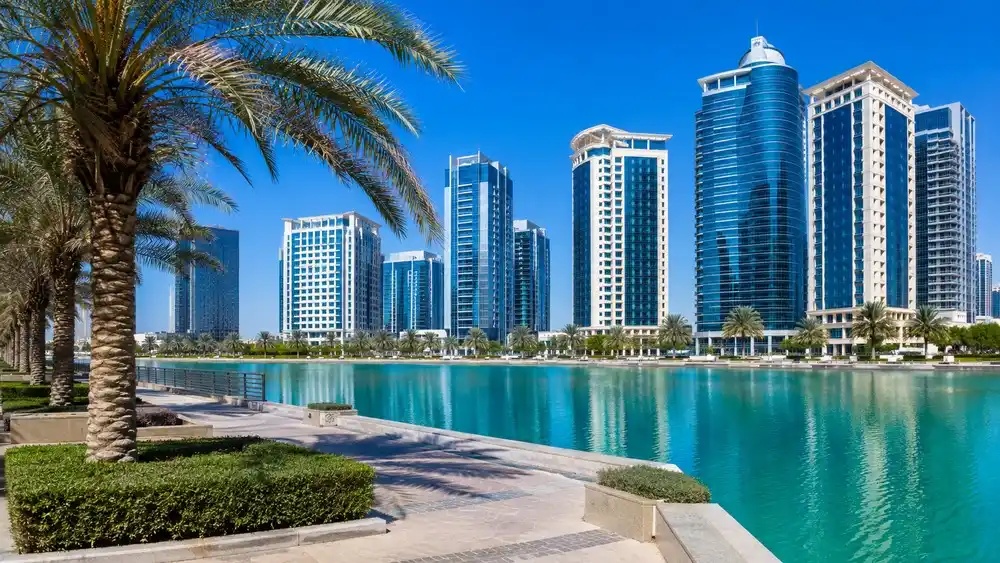 Pobřežní promenáda v Abu Dhabi s palmami a mrakodrapy nad Perským zálivem