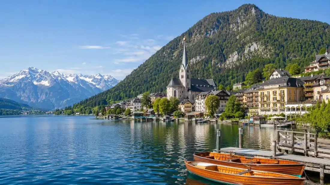 Zell am See na břehu jezera pod zalesněnou Schmittenhöhe, v dálce zasněžené vrcholy